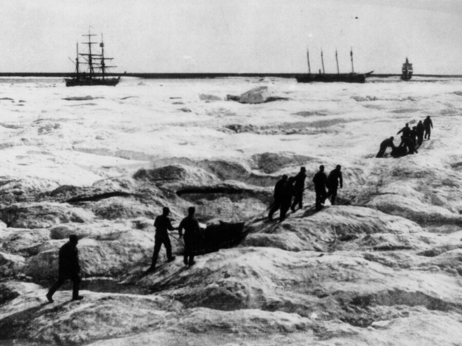 Photo: Crewmembers of the Revenue Cutter Bear haul supplies over frozen ground.